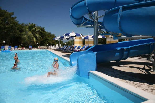Scivolo d'acqua blu che termina in piscina con persone.