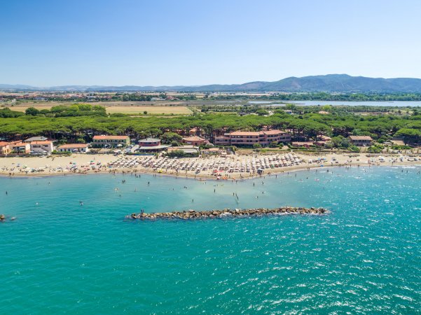 Spiaggia affollata con ombrelloni, mare e colline sullo sfondo.