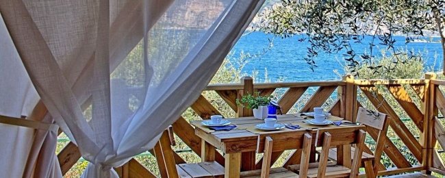 Tavolo in legno su terrazza con vista mare.