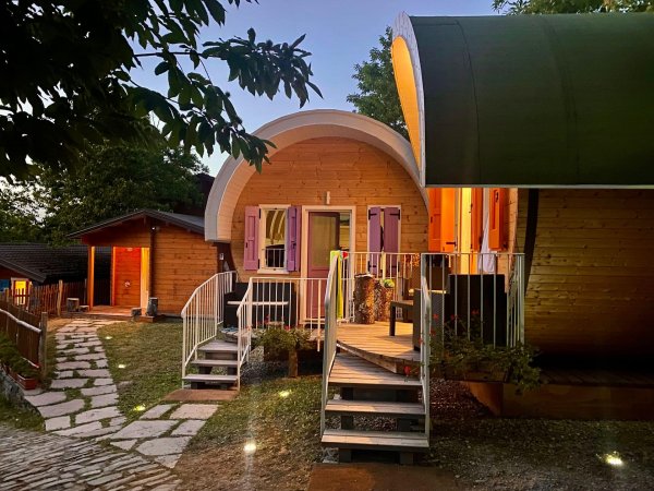 Casa di legno con luci serali e scala d'accesso.