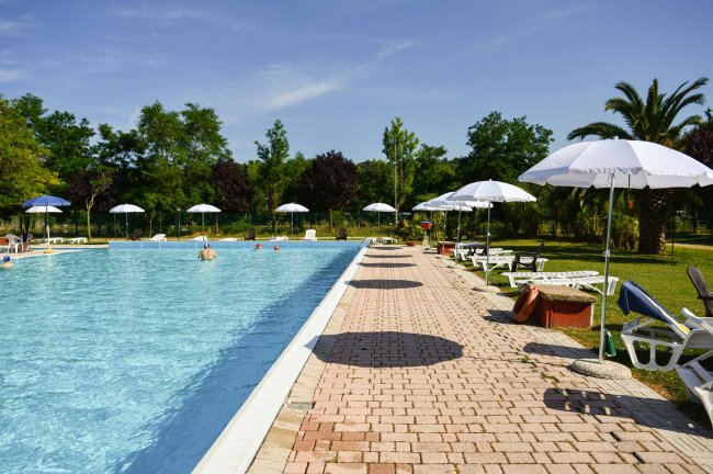 Piscina all'aperto con ombrelloni bianchi.