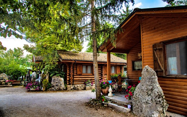 Due chalet in legno con fiori intorno.