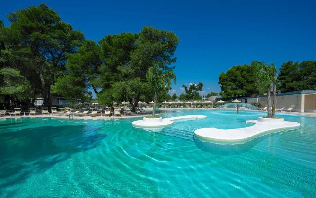 Piscina all'aperto con isole bianche e alberi.
