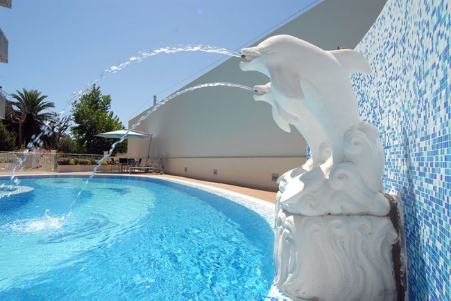 Fontana a forma di delfino spruzza acqua in piscina.