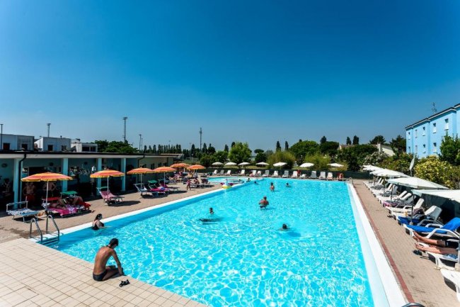 Piscina esterna affollata con lettini e ombrelloni colorati.