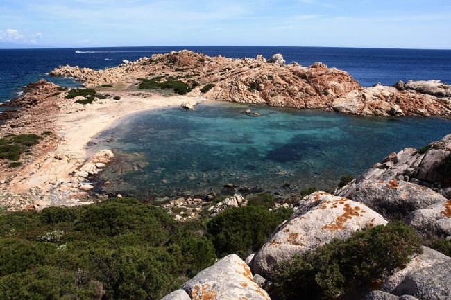 Spiaggia rocciosa con mare cristallino.