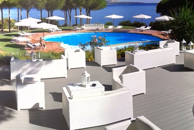 Area relax con divani bianchi vicino a una piscina circolare.