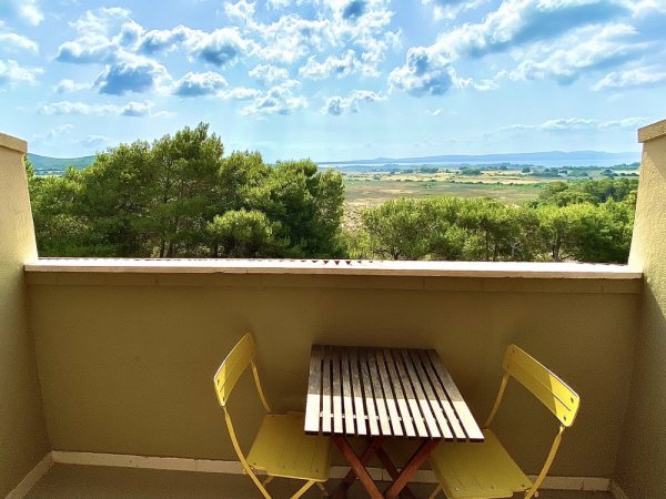 Tavolino con due sedie gialle su balcone vista campagna.