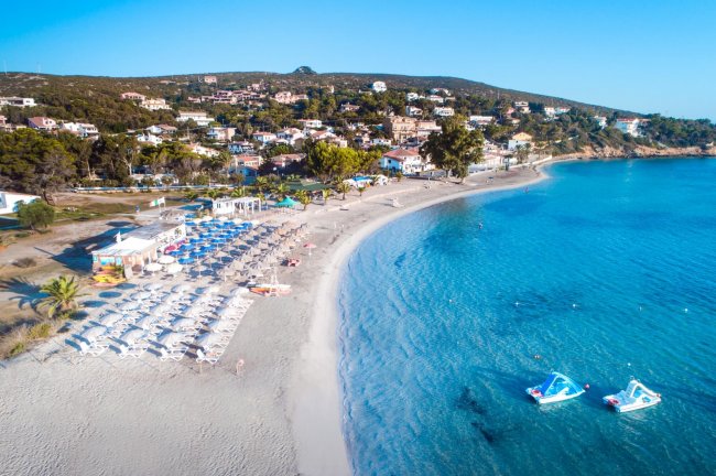 Vista aerea su spiaggia affollata e mare azzurro.