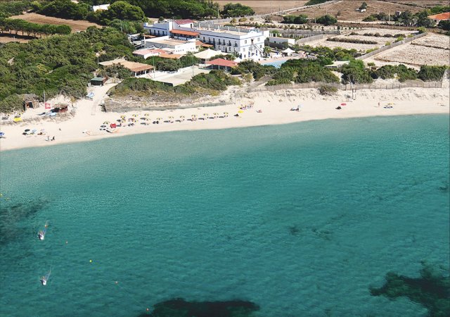 Vista aerea di un hotel e spiaggia con ombrelloni.