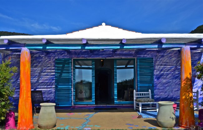 Casa colorata con persiane blu e vasi decorativi.