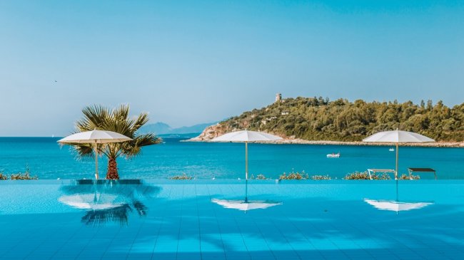 Piscina a sfioro con vista mare e ombrelloni.