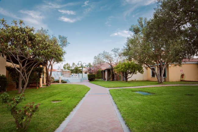 Cortile con sentiero tra piante e edifici.
