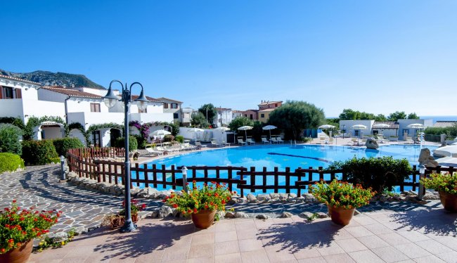 Piscina circondata da edifici bianchi e fiori.