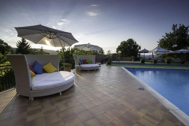 Area piscina con lettini e ombrelloni al tramonto.