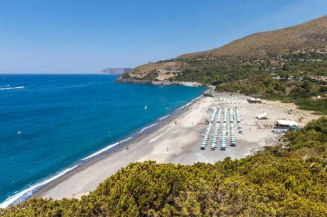 Spiaggia con ombrelloni e mare blu.