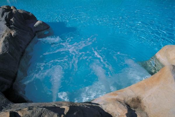 Vasca idromassaggio con rocce e acqua blu brillante.