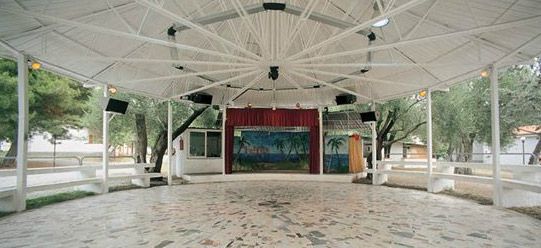 Anfiteatro coperto con pavimento a mosaico e palco decorato da una scena tropicale.