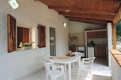 Portico con tavolo bianco e sedie, cucina sul fondo.