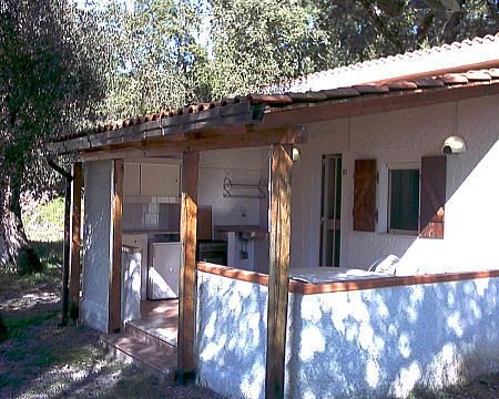 Un bungalow con una veranda in legno immerso nel verde.