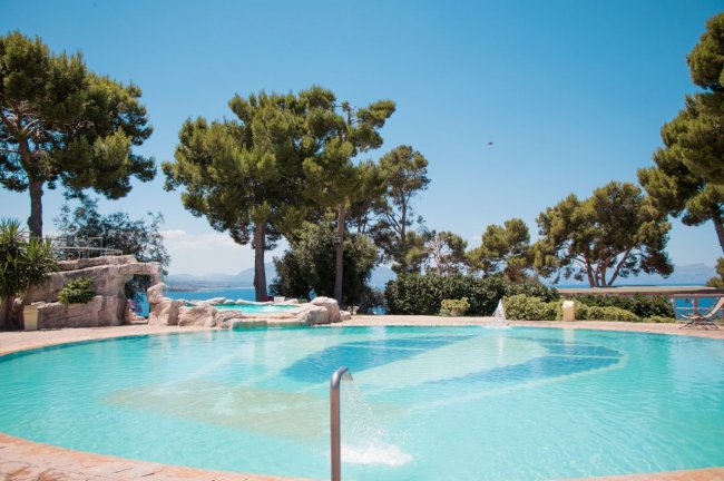 Piscina circondata da alberi e vista sul mare.