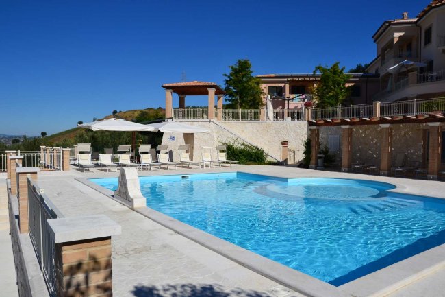Piscina all'aperto con lettini e ombrelloni.