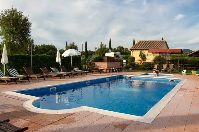 Piscina con sdraio e ombrelloni.