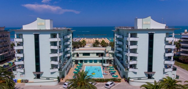 Complesso alberghiero con piscina centrale e vista sul mare.