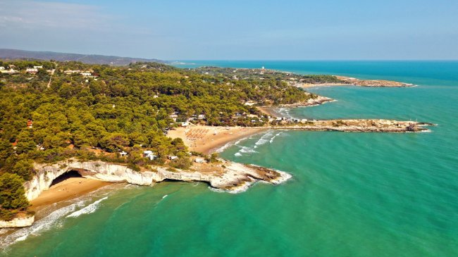 Spiaggia e promontorio verdeggiante sul mare.