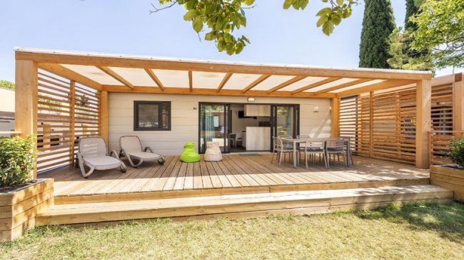 Terrazza di legno con sedie e tavolo, vista su giardino.