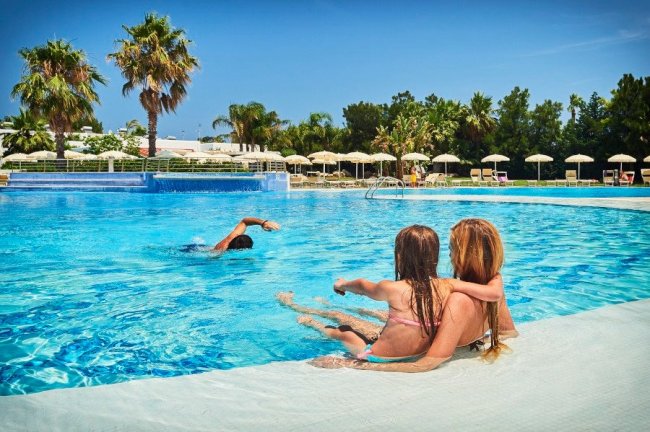Due persone in piscina sedute sul bordo.