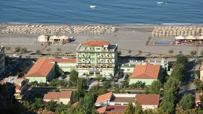 Edificio verde fronte mare con spiaggia.
