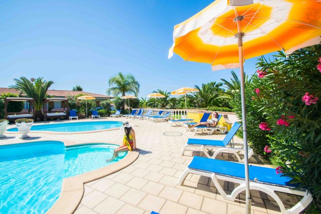 Piscina con lettini e ombrelloni gialli.