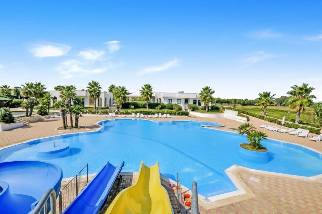 Grande piscina con scivoli e lettini.