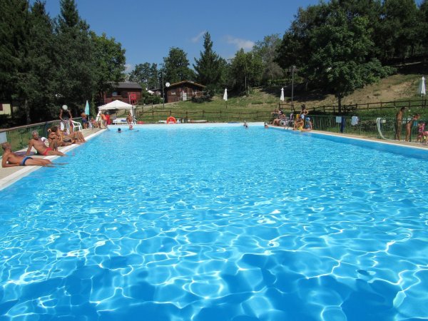 Ampia piscina all'aperto circondata da persone sedute.