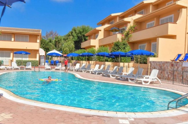 Piscina rotonda con lettini e ombrelloni blu.