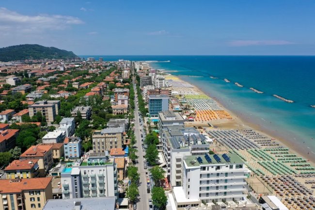 Panorama di una città costiera con spiaggia e ombrelloni.