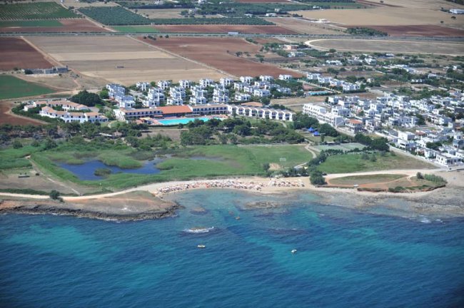 Vista aerea di un complesso residenziale vicino al mare con vegetazione.