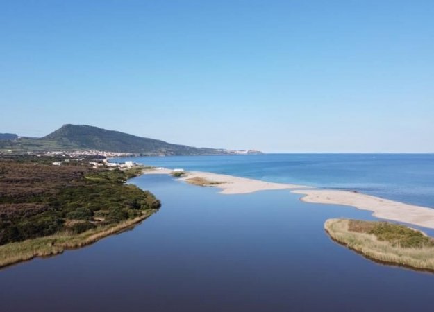 Vista aerea di costa con mare e laguna tranquilla.