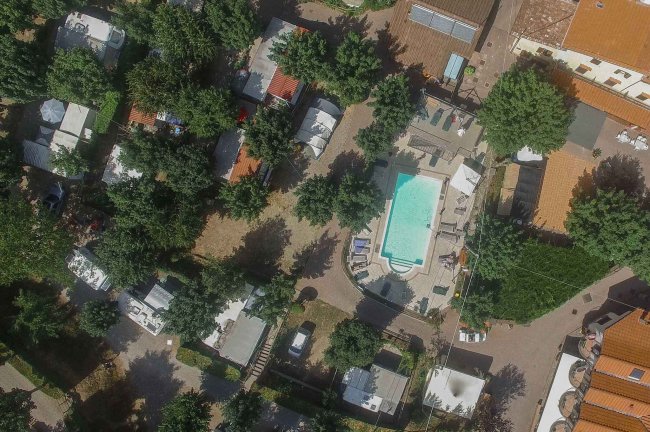 Vista aerea di un campeggio con piscina e alberi.