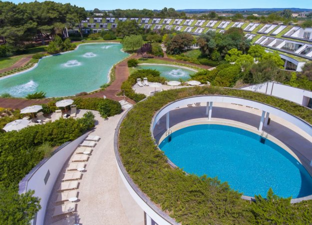 Vista aerea di piscine circolari con giardini intorno.