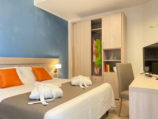 Stanza d'albergo con letto, armadio e scrivania.