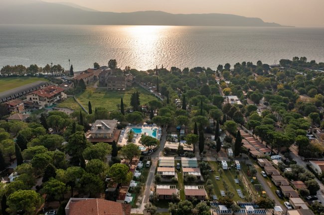 Vista aerea di un campeggio con piscina vicino al lago.