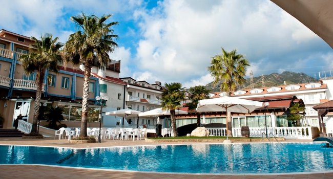 Piscina con palme e hotel sullo sfondo.