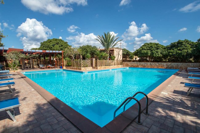 Piscina con lettini e cielo azzurro.