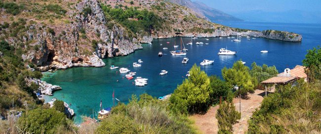 Baia con barche e scogliere verdi.
