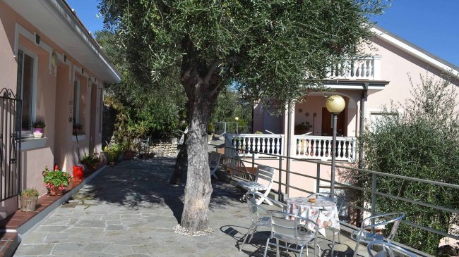 Cortile con tavoli e sedie vicino a una casa rosa.