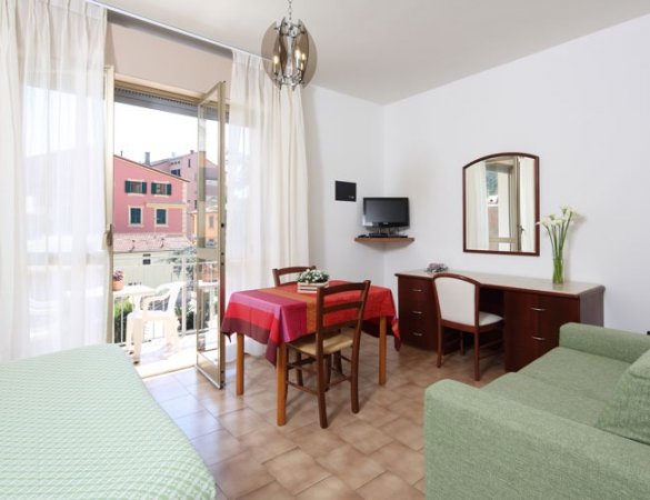 Soggiorno con tavolo rosso e porta-finestra aperta.