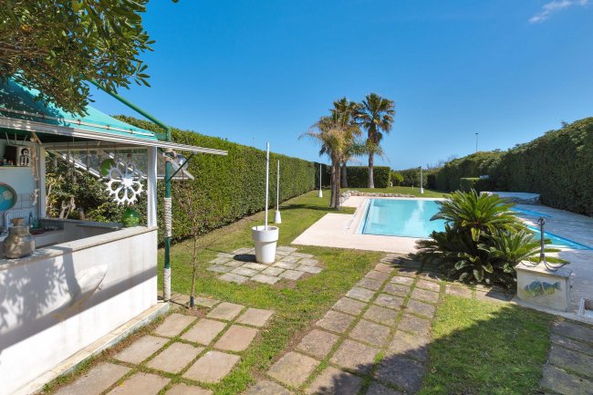 Giardino con piscina, palme e chiosco.