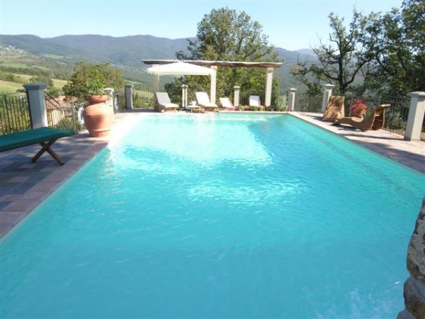 Piscina con vista su colline e lettini.